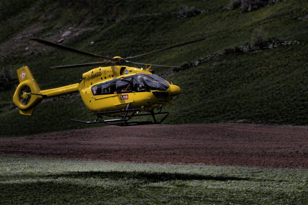 A bright yellow helicopter hovering above a grassy field, showcasing aviation technology.